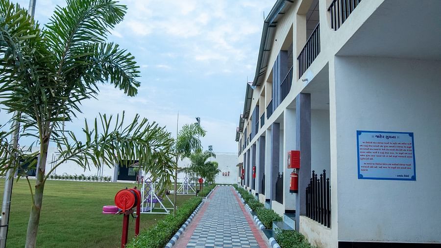 A well-maintained pathway with tiles, flanked by plants with the resort building in one side - VITS Select Diamond Resort, Sasan Gir