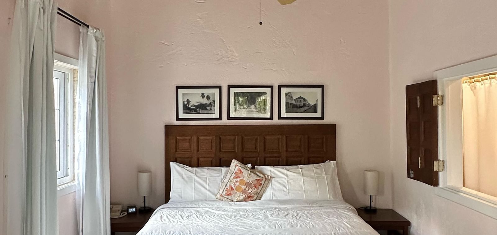 A bedroom with a bed covered in white linens and dark wooden floors | A Stone's Throw Away