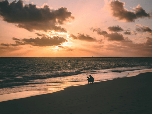 A serene beach scene at sunset with dramatic clouds and gentle waves