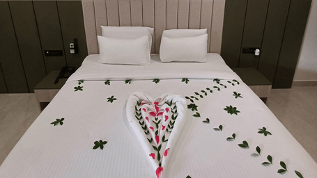 Ayana Resorts Hyderabad room featuring a king-size bed, green lounge chairs, modern interiors, and a spacious seating area.