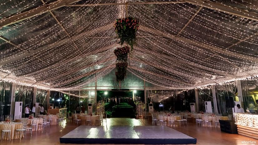 Elegantly decorated indoor event venue with draped lighting, floral chandeliers, and a stage in the center, creating a festive atmosphere at Black Thunder, Coimbatore