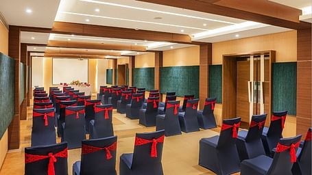 An image of huge wooden ceiling  hall with well arranged chairs at Grand Kakinada by GRT Hotels