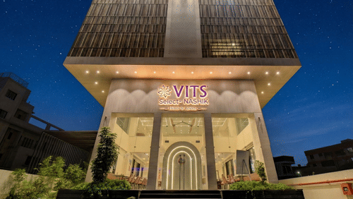 Exterior view of the VITS Select Nashik Hotels & Resorts building with signage and landscaped surroundings as seen during the night.
