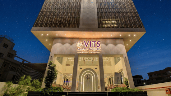 Exterior view of the VITS Select Nashik Hotels & Resorts building with signage and landscaped surroundings as seen during the night.