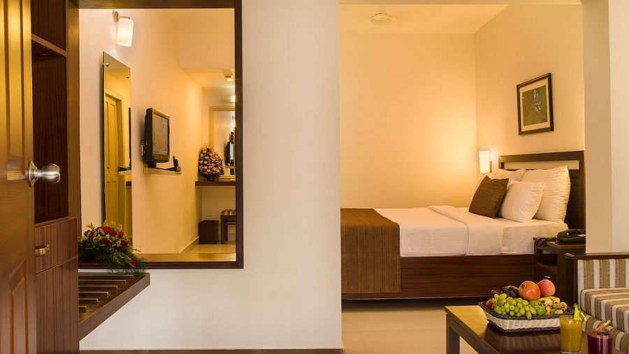 Room interior with a large mirror reflecting the bed and a portion of the room - Abad Copper Castle, Munnar