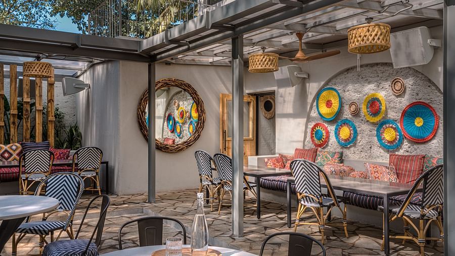 An overview of the outdoor seating arrangements with a mirror and handmade design on the wall at Village 36