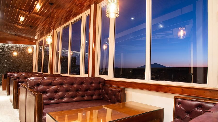 A seating arrangement of a bar in gangtok with leather couches and a well furnished table - Summit North Star, Gangtok