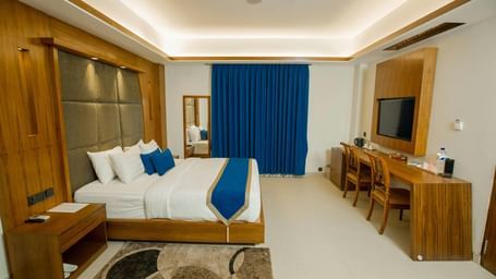 A spacious room featuring a large bed, a practical desk, a cosy seating area, and stylish modern decor