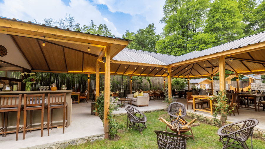 An open dining area with lavish wooden interiors, atttic style roof, wooden chairs and table at Bedzzz Xclusiv Baikunth, Manali