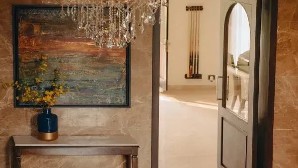 Interior hallway with a chandelier, wooden console table, artwork, and arched doorways at Karma Chalets.