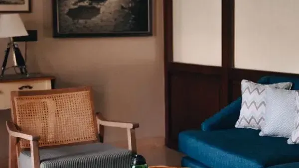 Cosy indoor seating area with blue and wooden chairs, a bottle on a round wooden table at Karma Chalets.