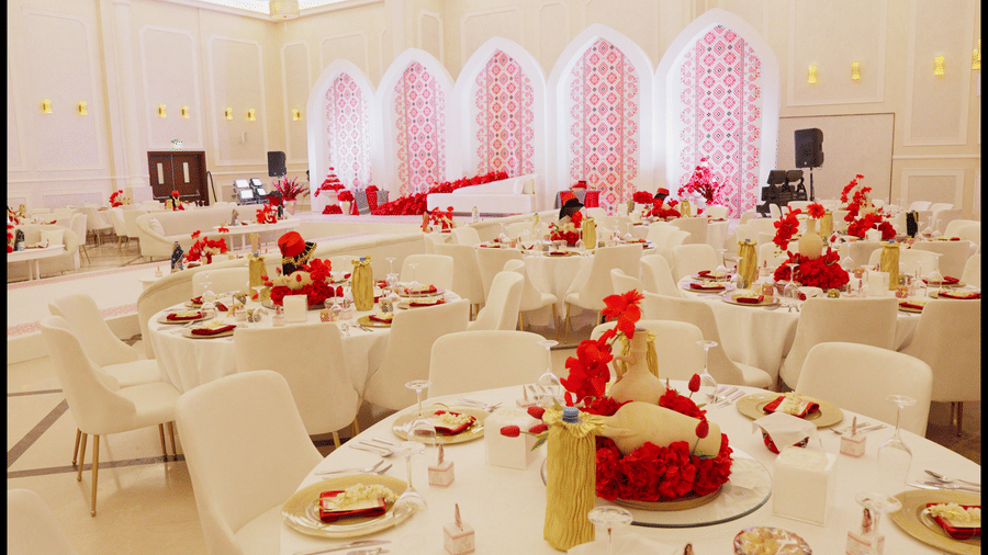 A narrow, vertical view of a decorated banquet hall at La Maison, Doha, showing tables set for dining.