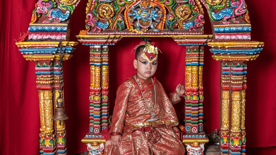 A colorful, ornately carved wooden shrine housing a traditional Hindu deity idol inside a historic temple in Bhaktapur, Nepal.