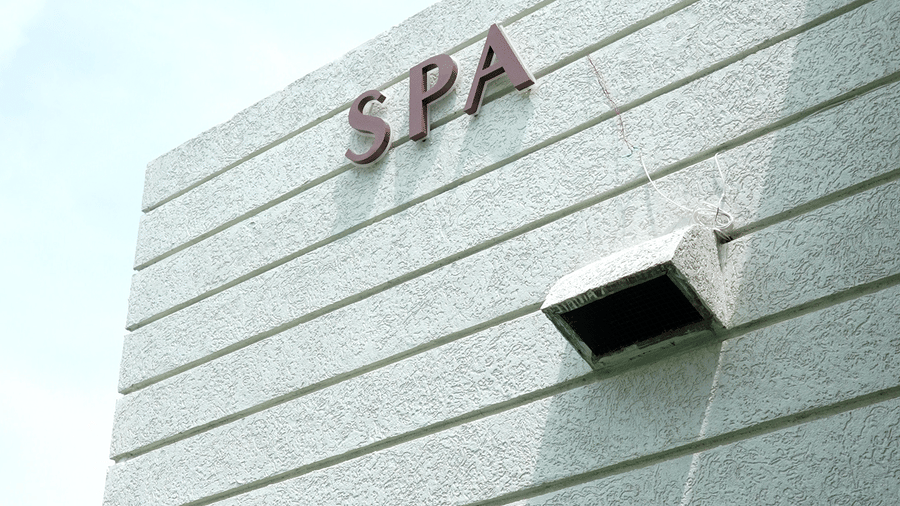Exterior of a modern building with a minimalist white facade and a sign at the top at Hotel Hukam's Lalit Mahal.