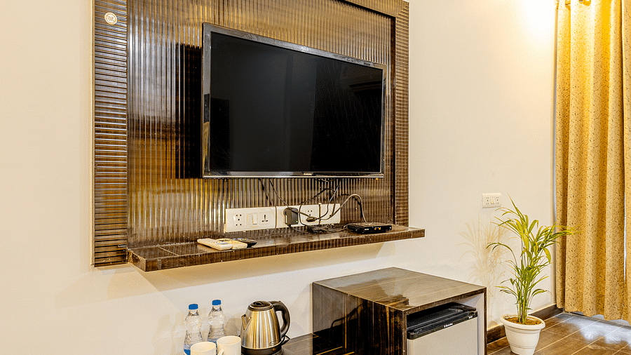 A wall mount television and small tables in the suite at Lime Tree Hotels and Banquet Hall Near Huda Metro, Gurgaon