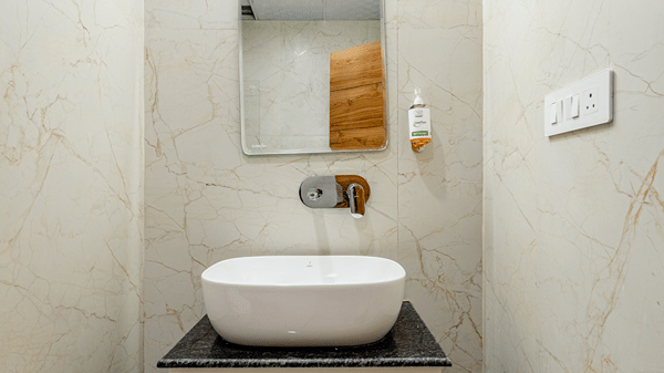 Sleek counter-top ceramic washbasin sitting on a modern wooden vanity unit with a back lit mirror.