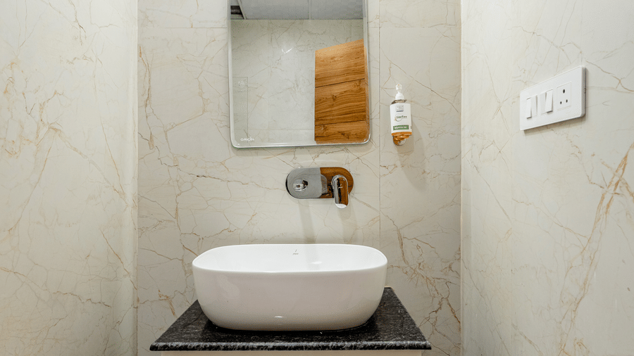 Sleek counter-top ceramic washbasin sitting on a modern wooden vanity unit with a back lit mirror.