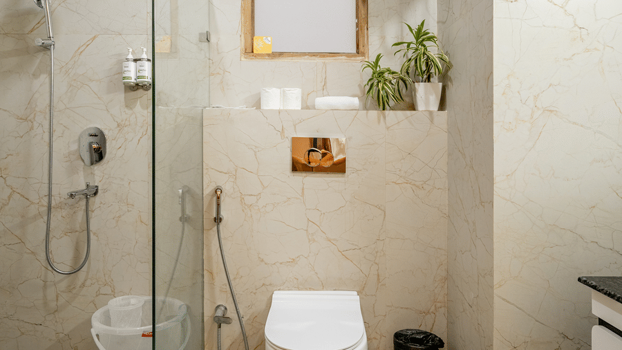 Modern hotel bathroom featuring a glass shower cubicle, wall-mounted toilet, and tiled floors.