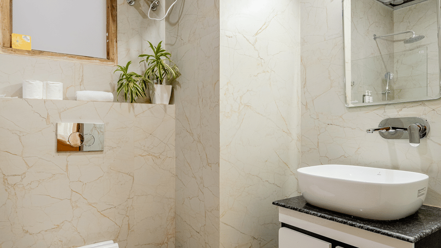 Contemporary hotel en-suite bathroom with a white ceramic washbasin vanity unit and a wall-mounted toilet.
