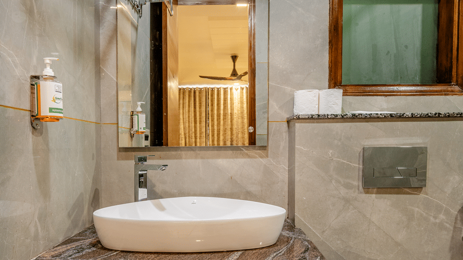 Modern bathroom vanity unit with a white ceramic basin, dark wooden cabinet, and large mirror.