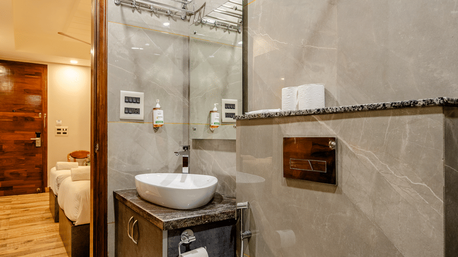 Compact modern bathroom featuring a round mirror, a white vessel sink, and a wall-hung toilet.