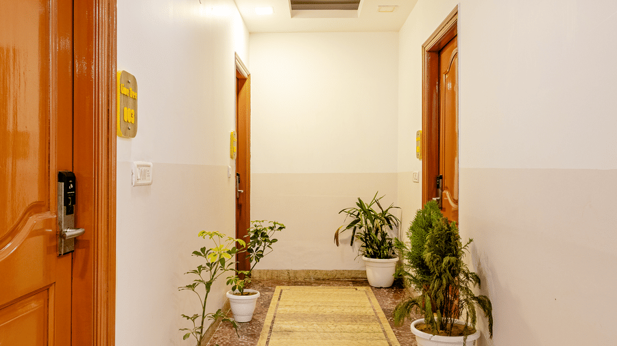 Bright hotel corridor leading to guest rooms with modern interiors.