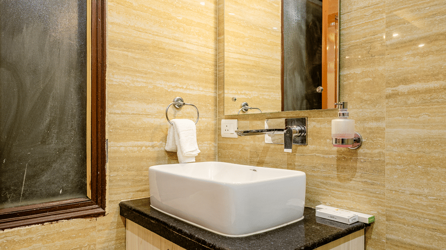 Hotel bathroom with a stylish wash basin, mirror, and modern countertop.