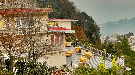 Exterior view of a multi-storey resort building during a golden sunset over the hills | Voyage Rodhi Resort