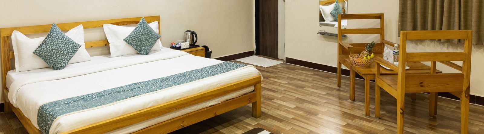 A spacious guest room with a bed, artwork, and wooden table and chairs at Daksh Resort & Amusement Park.