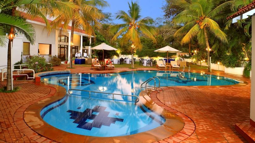 An overview of the Swimming pool at Sangam Hotel, a Hotel Near Thanjavur Railway Station, with trees in view.