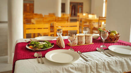 A set dining table with a red runner and white crockery in a bright, airy restaurant at Indus Serenity Retreat.