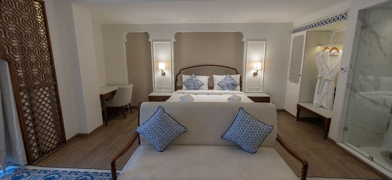 Front view shot of the Purna bedroom featuring a small couch in front of the double bed at Bhagirathi by RDB Atishay.