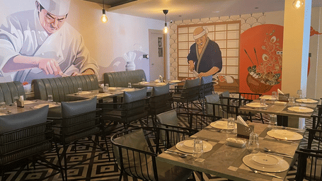 Restaurant seating area featuring artistic wall designs and neatly arranged tables at Hotel Kyzen HiTech City – Your Zenly Stay