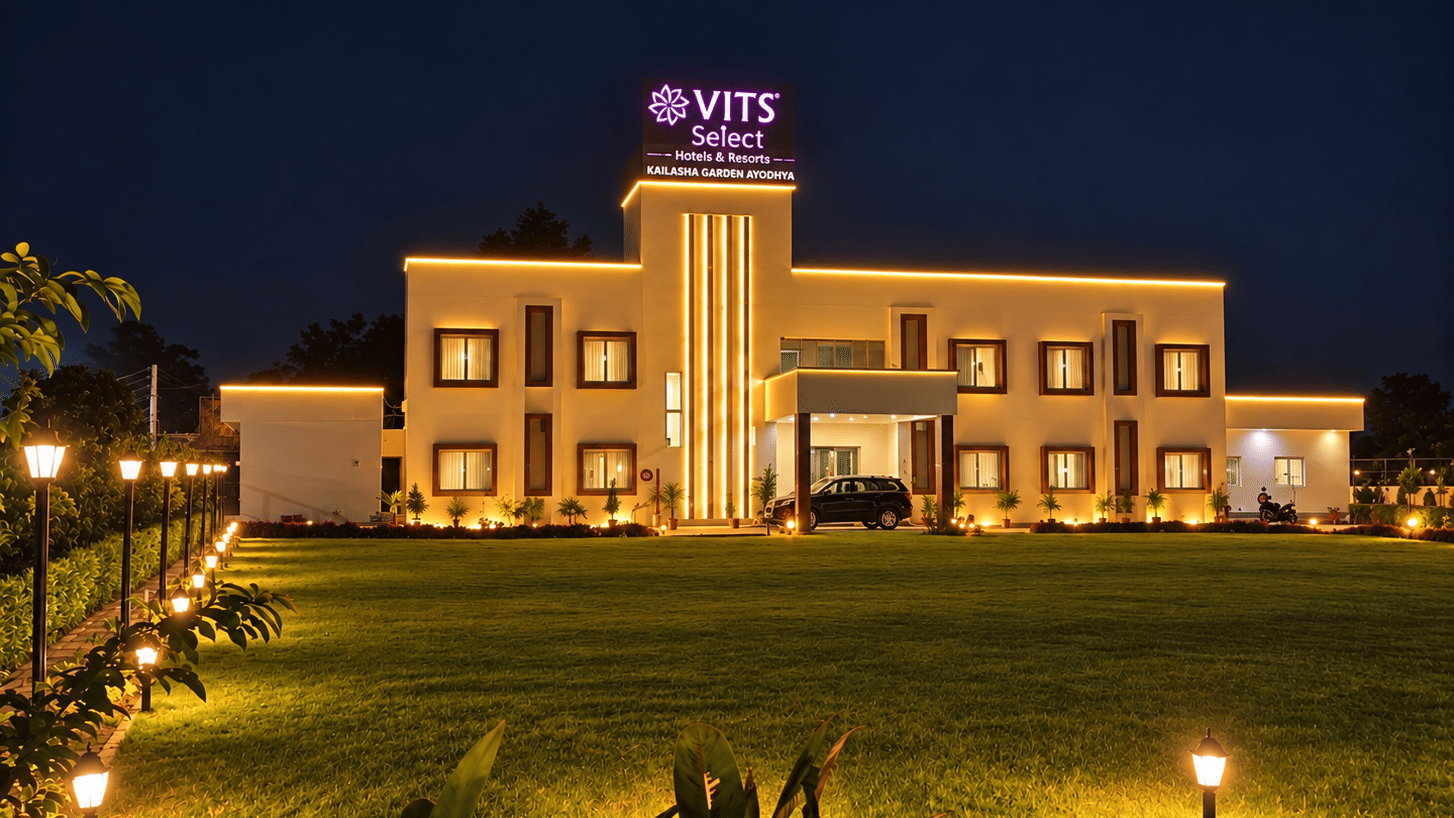 Hotel building illuminated at night with a landscaped lawn and pathway lighting.