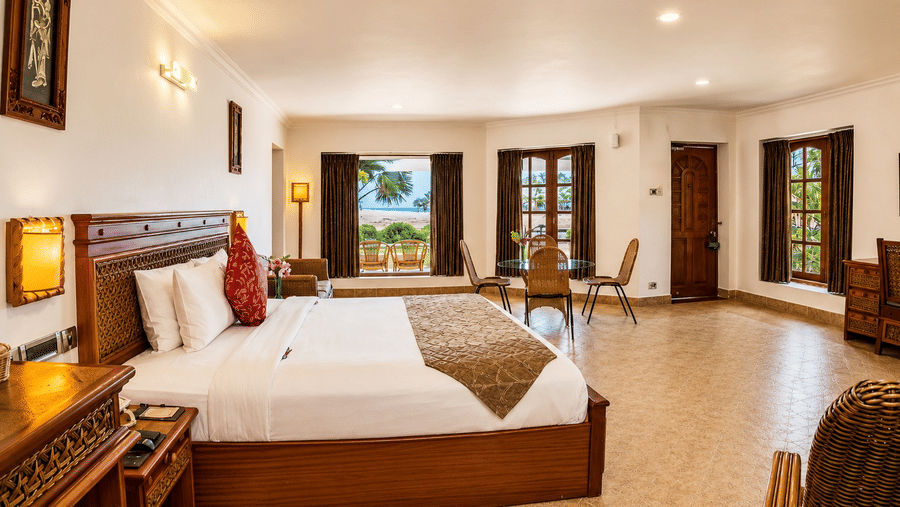 Premier Golf Vista Cottage bedroom with a king bed, arched windows, and views of lush greenery at Chariot Beach Resorts, offering a serene retreat