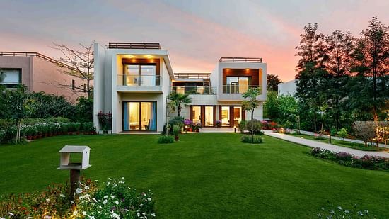 An image of the Woodpecker Villa at Karma Lakelands with a green lawn and garden in front