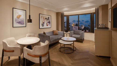 Elegant living area of a spacious suite room at The Residency Chennai, showcasing a stylish sofa set, framed artwork on the walls, and a round table.