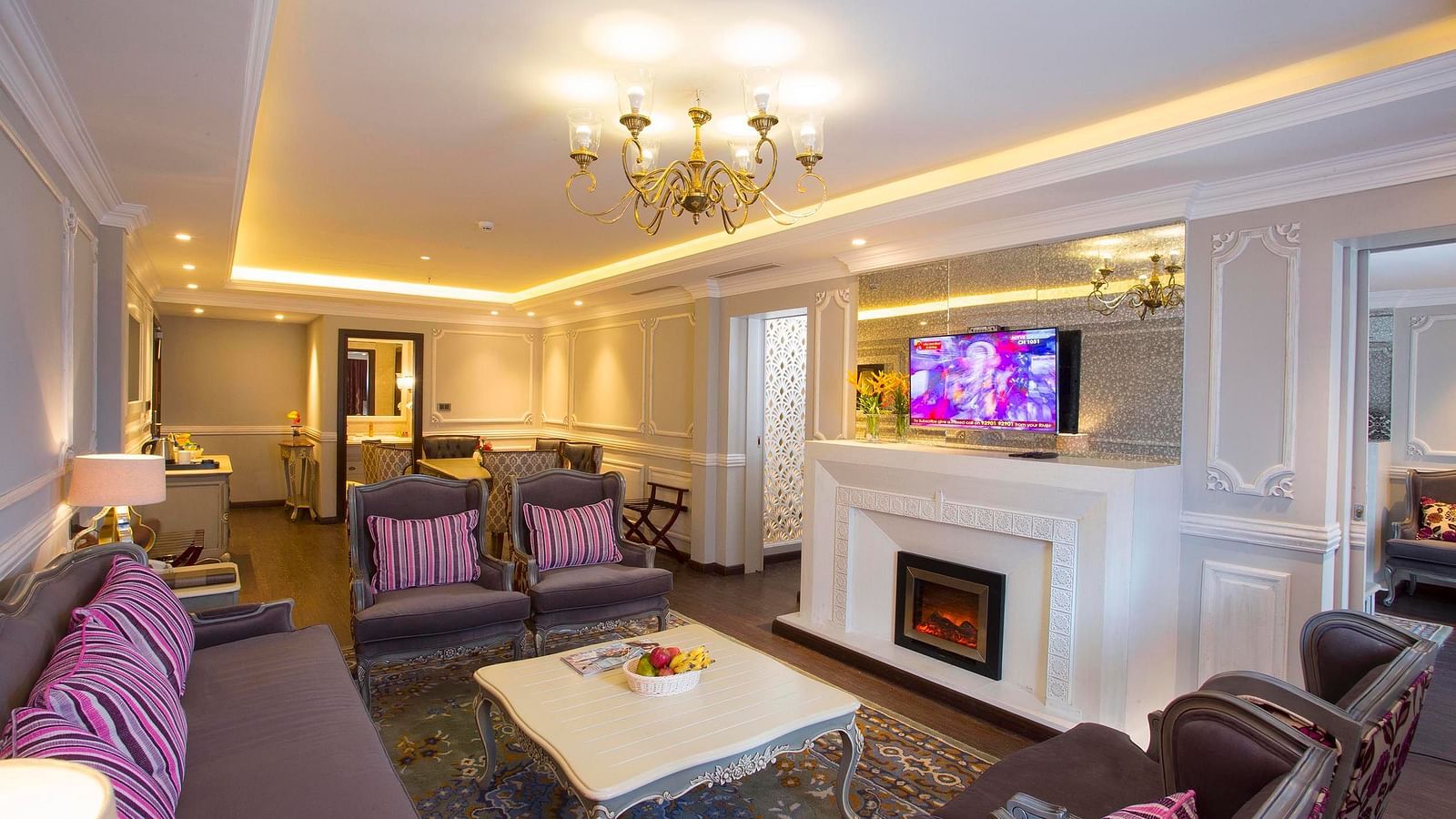 Suite living area with furniture around the table and a wall-mounted television above the fireplace