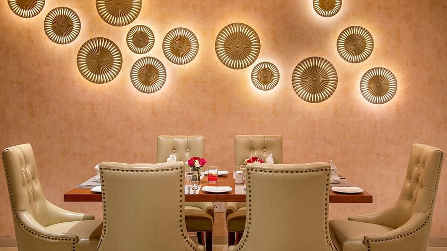 A private dining room with a decorative wall and a set table for a more intimate gathering - SK Lords Inn Ahmedabad
