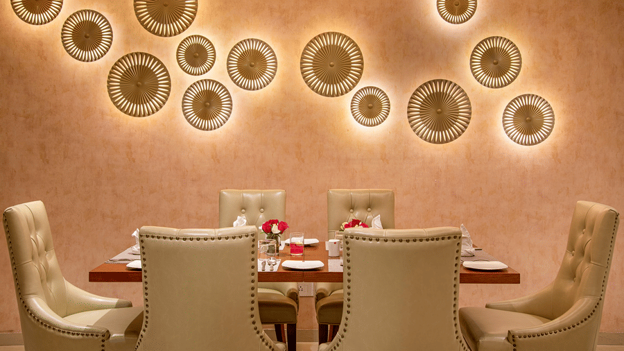 A private dining room with a decorative wall and a set table for a more intimate gathering - SK Lords Inn Ahmedabad