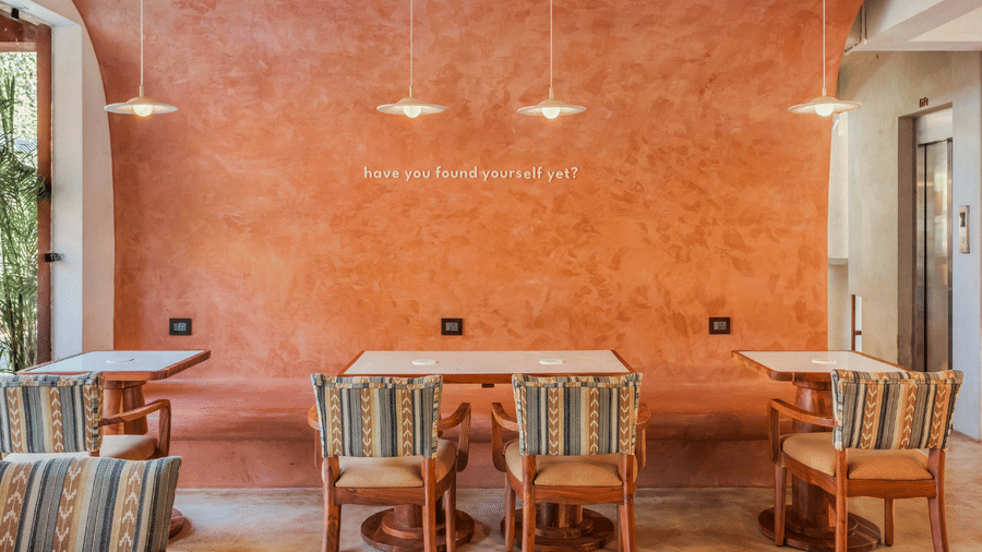 Book direct and get 31% off at Unseen Boutique Hotel Assagao Goa featuring a cozy seating area with two patterned armchairs a checkered rug and warm string lights on a wooden ceiling.