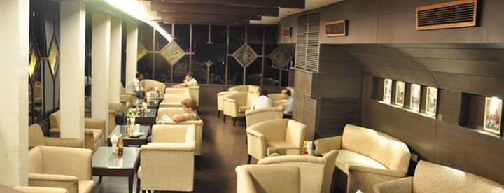 A brightly lit seating area with white leather sofas and central air-conditioning at 24 Karats Bar - Hotel Gold, Panipat
