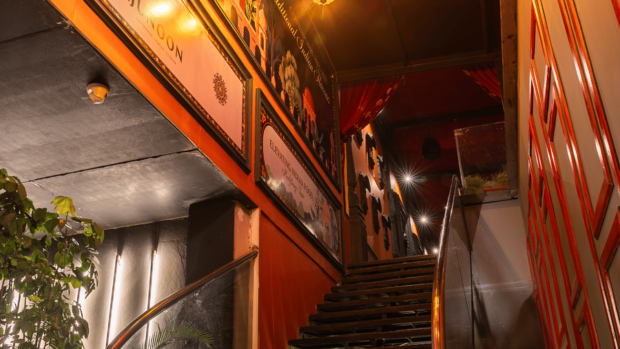 A staircase with colourful hanging lanterns and decorative walls on either side at Infiniti Hotel, Indore.