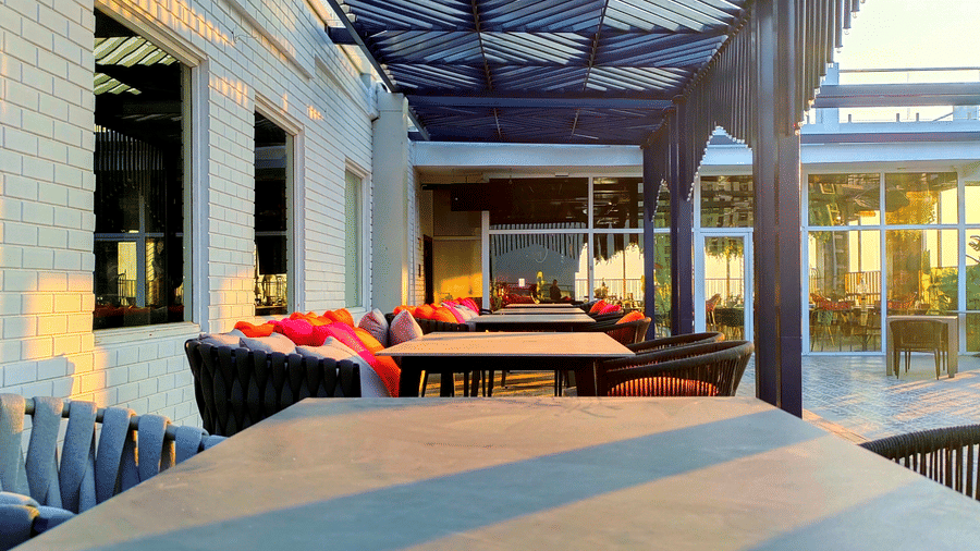 An empty dining table under a shaded area with sun rays falling over it at the rooftop pub, Kensho at Leroy Grand, Yeshwanthpur.