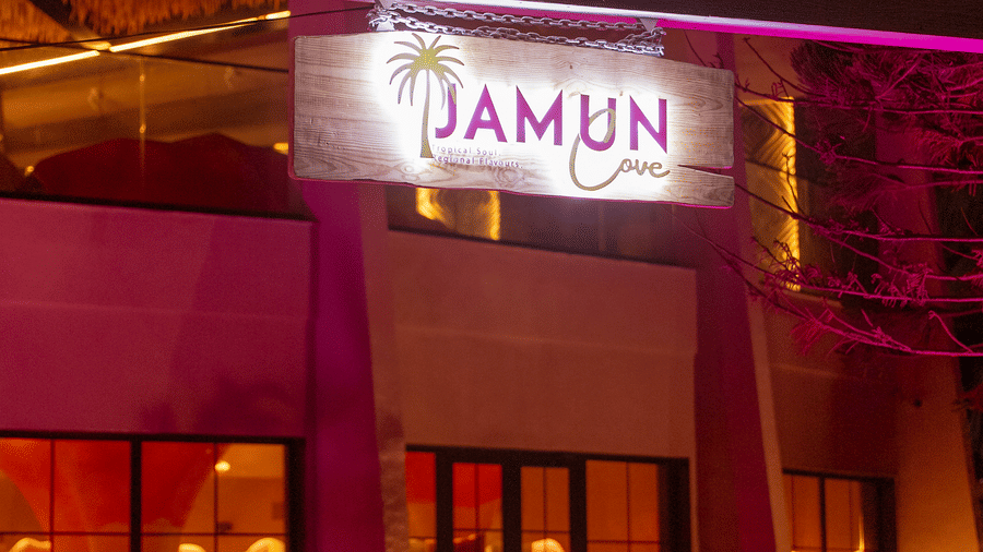 Exterior entrance of Jamun restaurant illuminated with purple lighting at night - Symphony Resorts