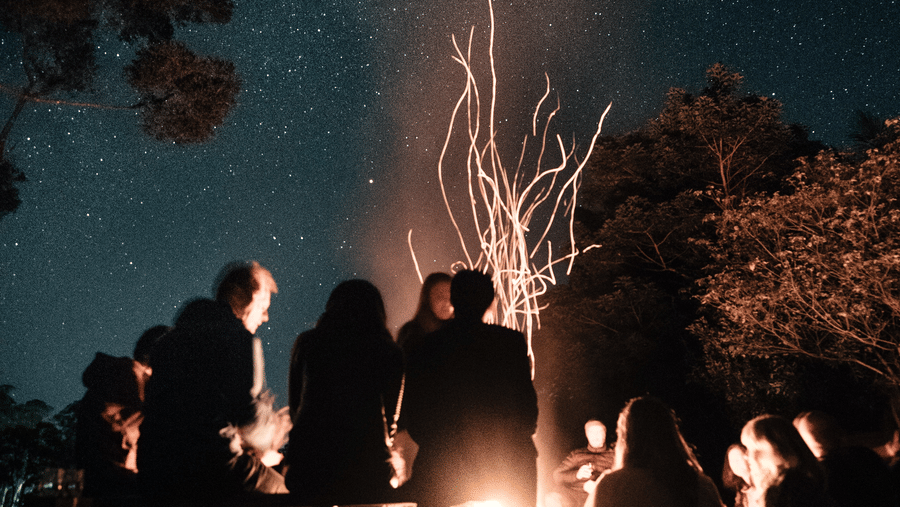 people enjoying a time surrounding the bonfire during night time