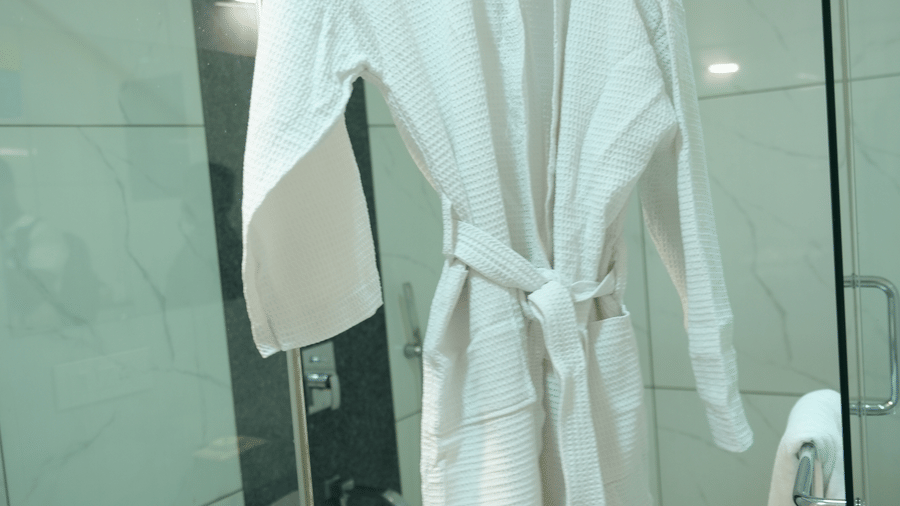 Bathroom area featuring bathrobes and glass shower enclosure at Pipul Utkal Continental, Jharsuguda.