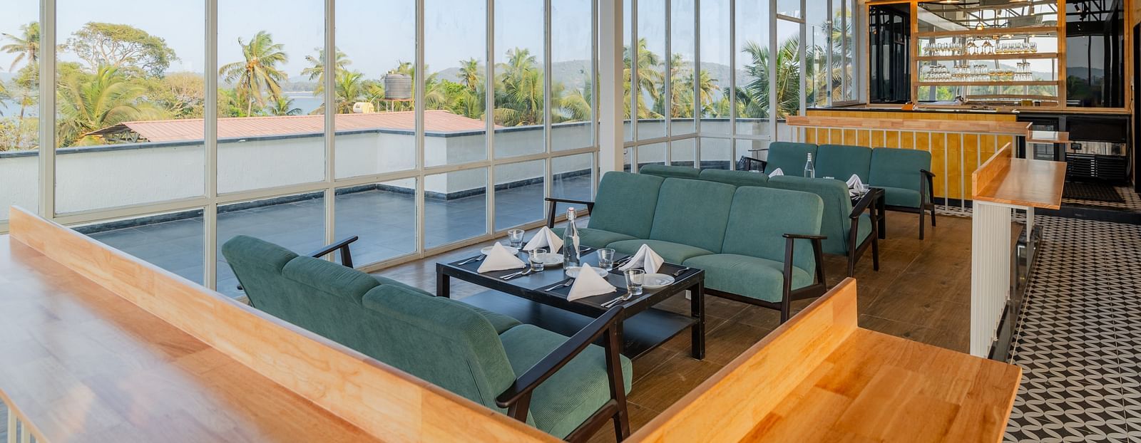 Spacious cafe interior with large windows and comfortable seating at Bedzzz Xclusiv Morjim, Goa