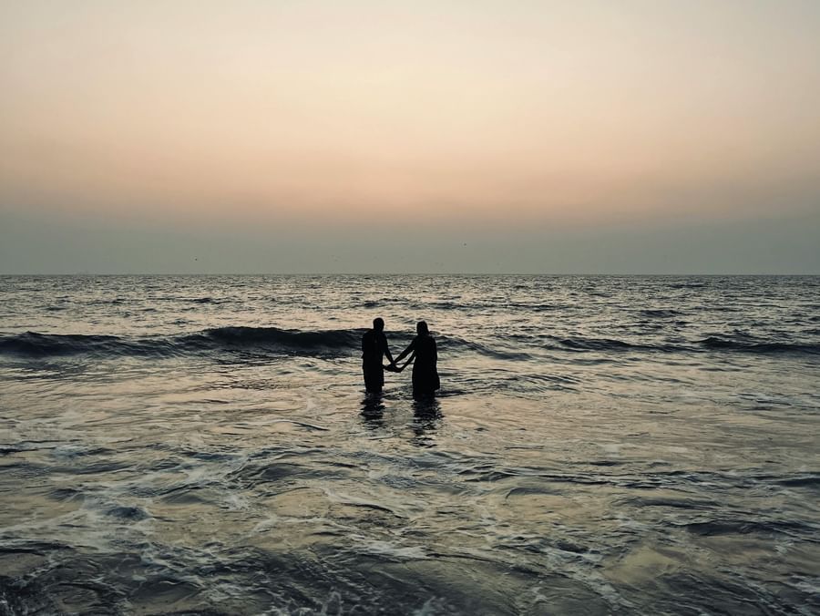 People standing in the ocean during dusk, with soft lighting and a calm atmosphere.