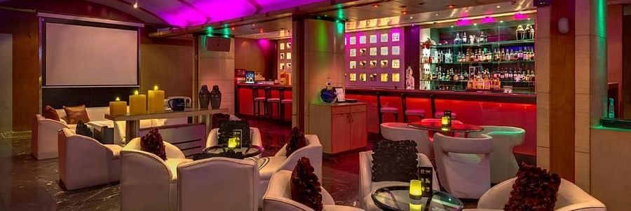Chic lounge bar with vibrant lighting, plush seating, and a well-stocked bar – Hotel Hindusthan International, Kolkata.